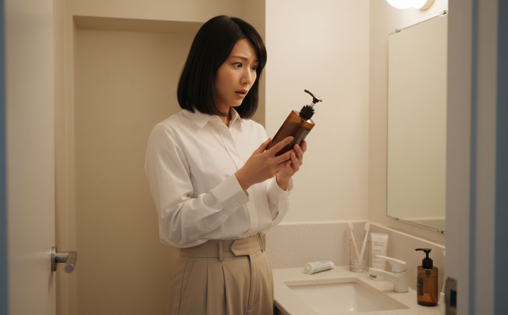 トリートメントの表示を見て驚く女性